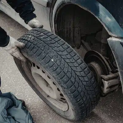 Mechanic lifts tire onto wheel hub, completing change at tire shop waco tx today