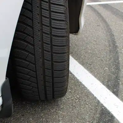 Close-up of car tire tread by curb, prompting tire alignment near me inspection for wear