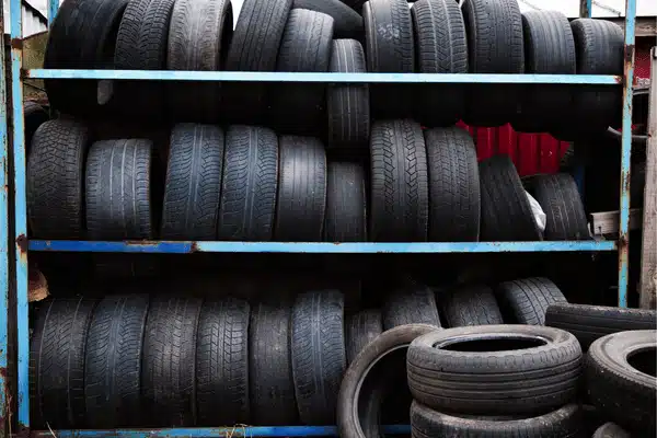 Rows of stacked used tires on metal racks, suggesting tire alignment near me service inventory