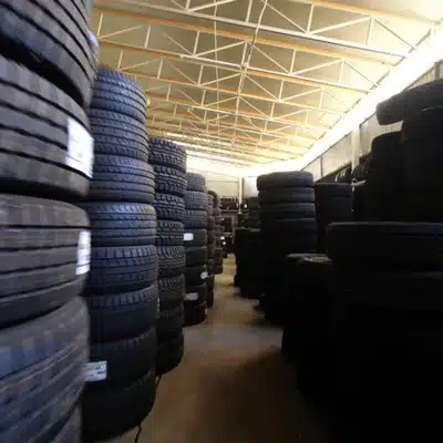 Aisle of tall tire stacks lines storage space, highlighting capacity at used tire shop facility