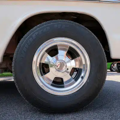 A close-up vehicle tire is mounted on a shiny wheel outside a tire shop waco tx service area