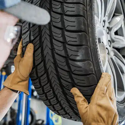 A technician wearing gloves installs a tire at a tire shop waco tx auto service bay
