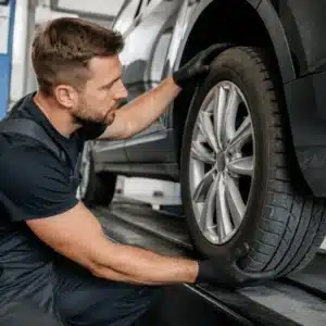 A tire specialist inspects the tread and condition of a vehicle tire in a professional automotive service bay